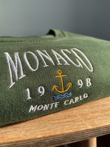Close up detailed embroidered Monaco design, photographed on forest green sweatshirt.