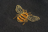 Close up of embroidered golden bumble bee on a black sweatshirt.