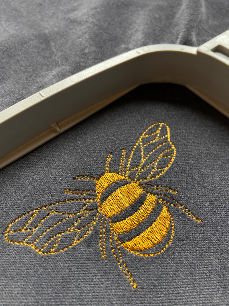Close up of embroidered bee on Dark Grey cushion.